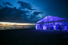 Vue nocturne d'un chapiteau sur plage - le contraste des couleurs invite à la fête mais aussi à une certaine sérénité